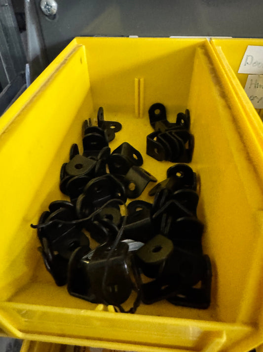 Assorted black steel mounting L brackets in a yellow bin